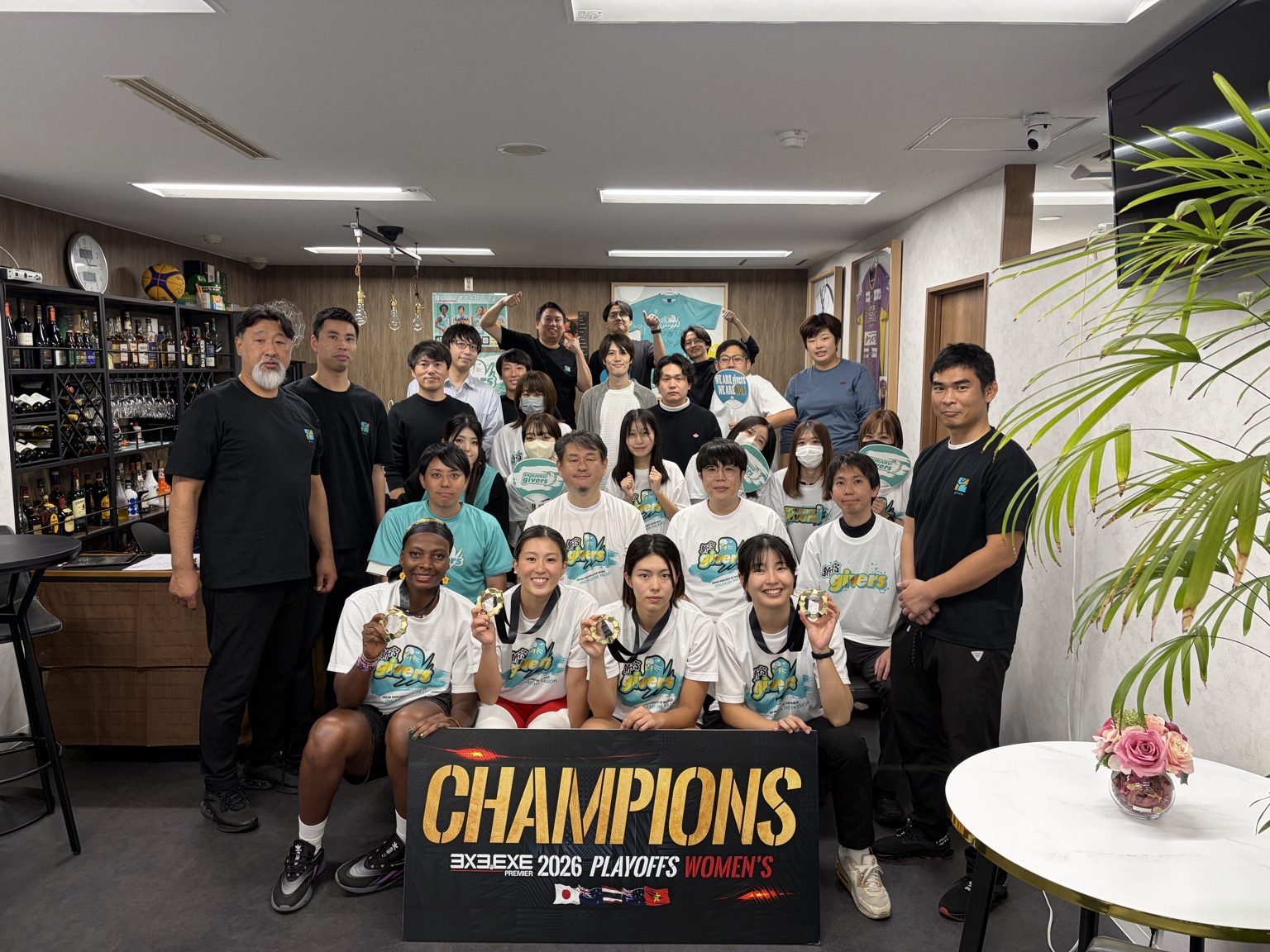 優勝ボードを囲んで集合写真に収まる新宿GIVERSの選手と株式会社giversの本部メンバー